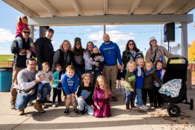 A group of family, friends and kids smile for a photo during Homecoming 2023